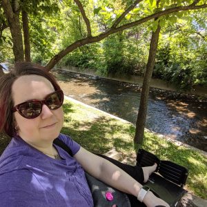 Photo of Rebecca in her wheelchair by a creek